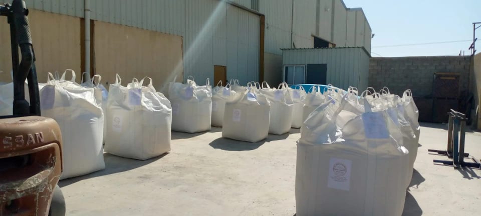 Jumbo bags of silica sand in front of the warehouse, forklift at the left