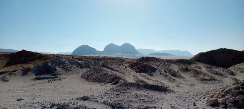 Desert landscape with mountains under a clear sky, white sand in the foreground