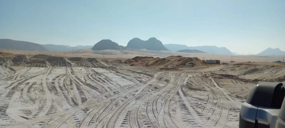 Desert track and mountains at the mine, with a vehicle at the right edge