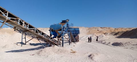 Screening plant with a conveyor belt and workers in the distance