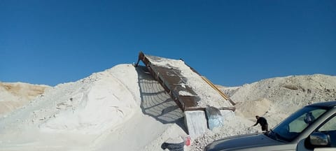 Sand pile with a conveyor feeding it, a vehicle beside it