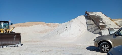Wheel loader beside the white sand pile and its conveyor